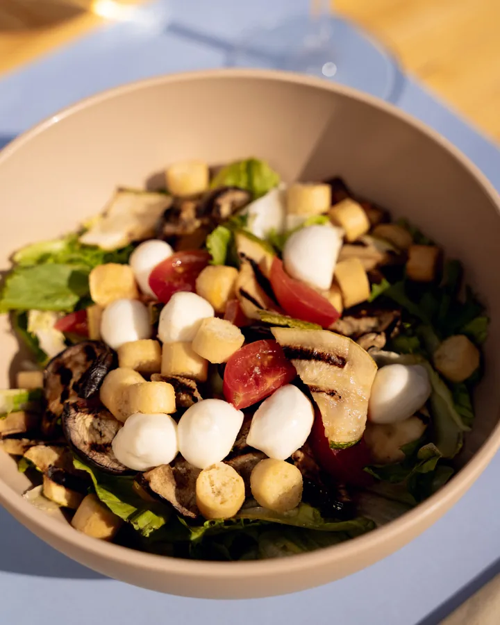 Insalata mista in ciotola con mozzarelline, verdure grigliate, pomodorini e crostini