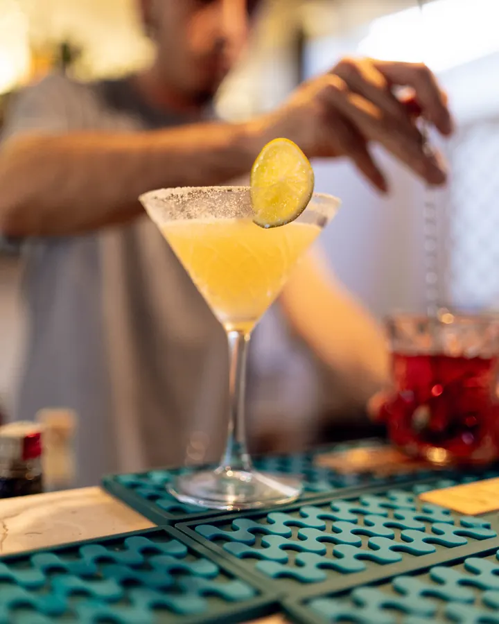 Margarita col bordo di sale e la fetta di lime, il barman al lavoro dietro