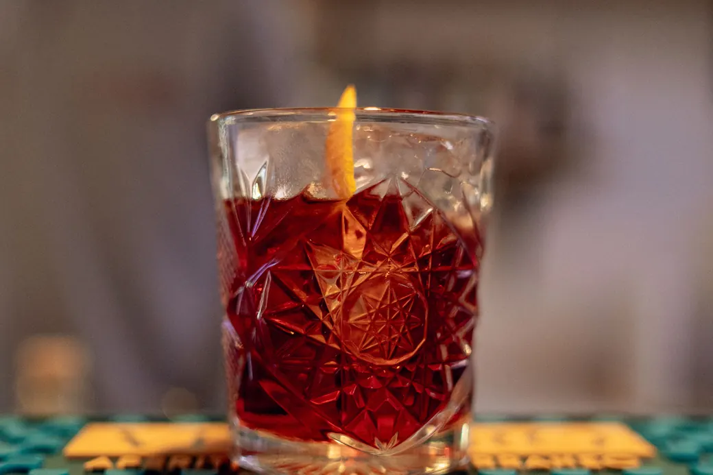 Negroni servito al bancone, il barman sullo sfondo