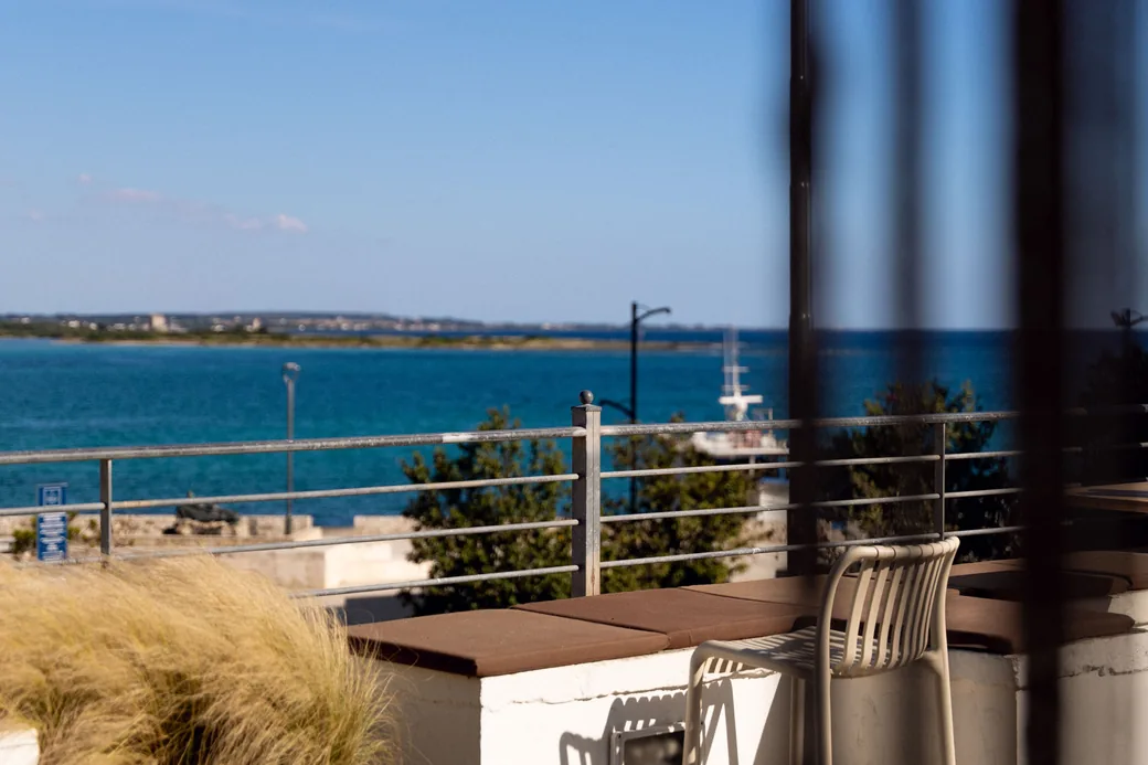 I tavoli della terrazza al tramonto, le palme del lungomare dietro