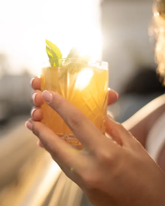 Una mano che tiene un cocktail in controluce, la sera